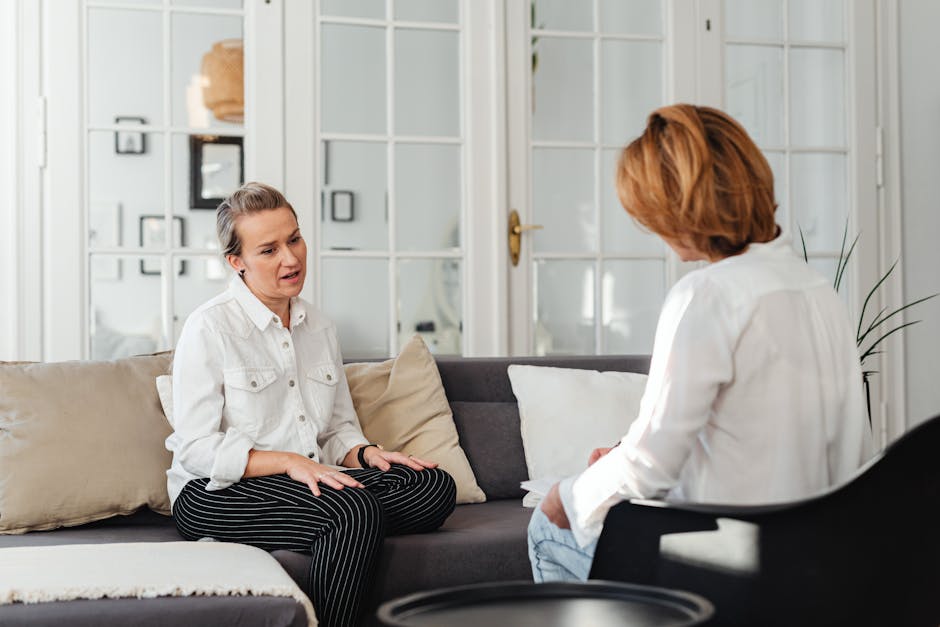 About Two women having an intimate conversation on a sofa in a cozy indoor setting.